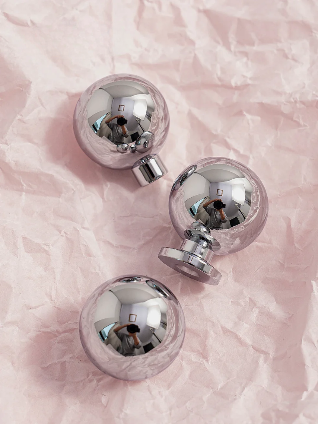 Silver spherical door handles on a pink marble surface