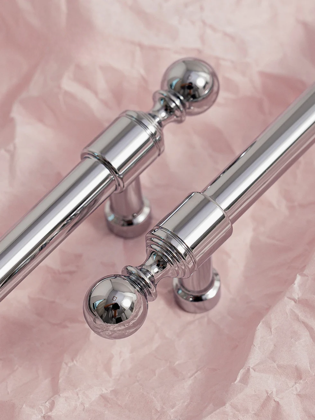 Silver towel bar with spherical ends on a pink textured background