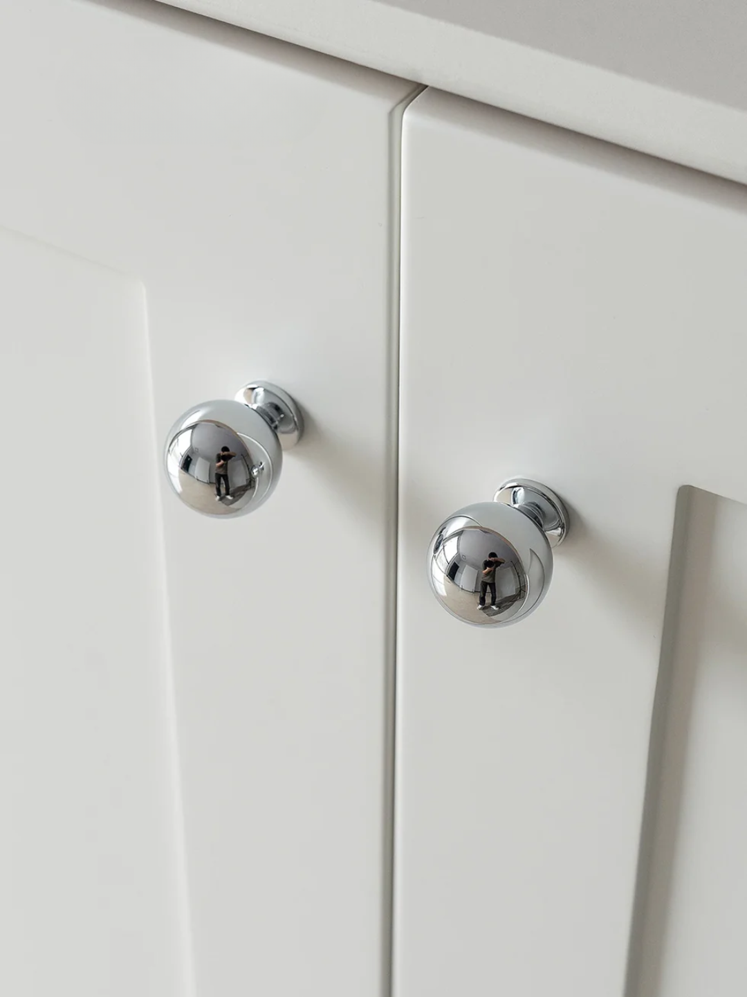 Close-up of white cabinet doors with chrome knobs