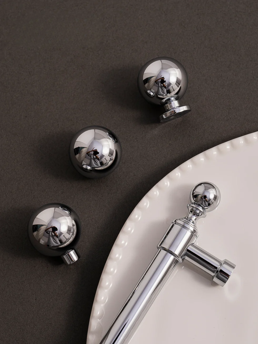 Chrome and black door handles on a dark surface with a white plate.