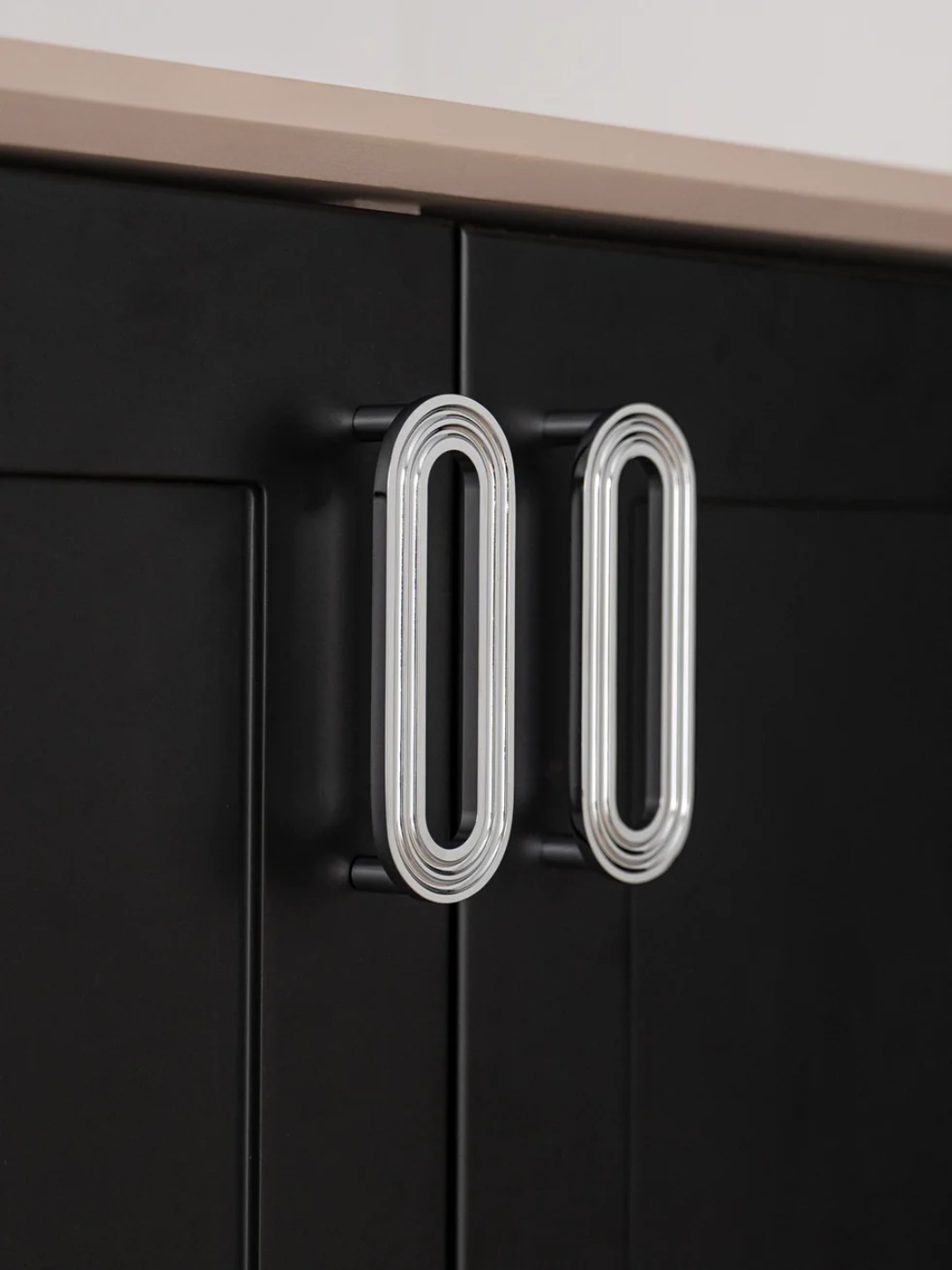 Black cabinet with a modern silver handle on a neutral background