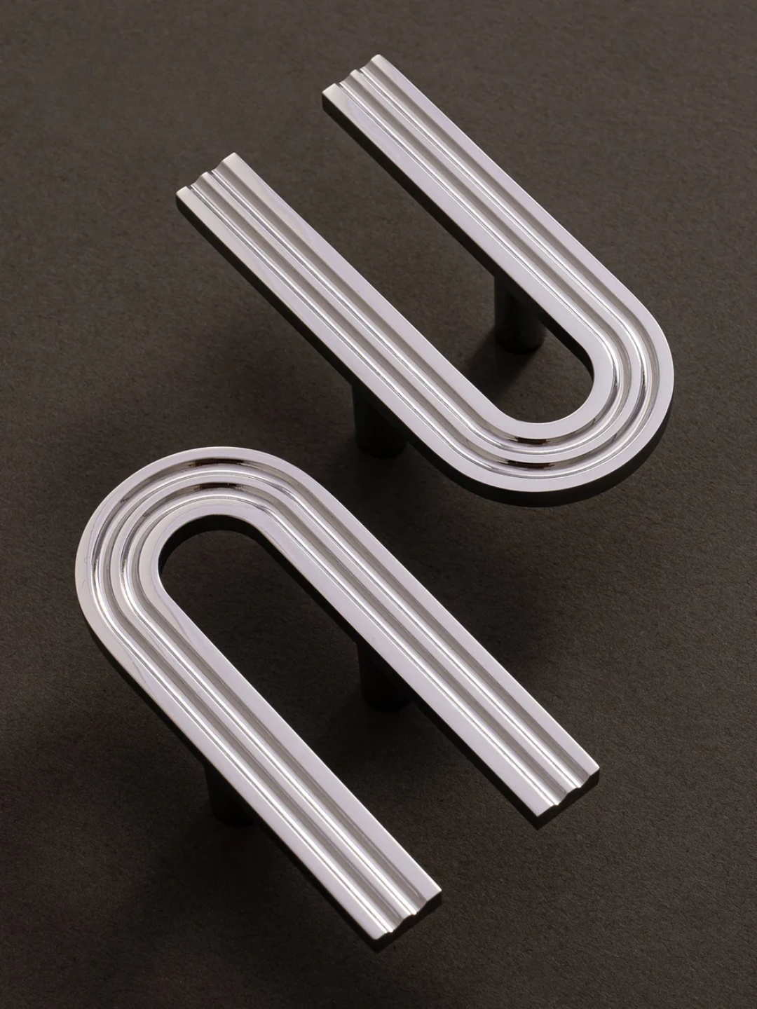 Two U-shaped metal brackets on a dark background