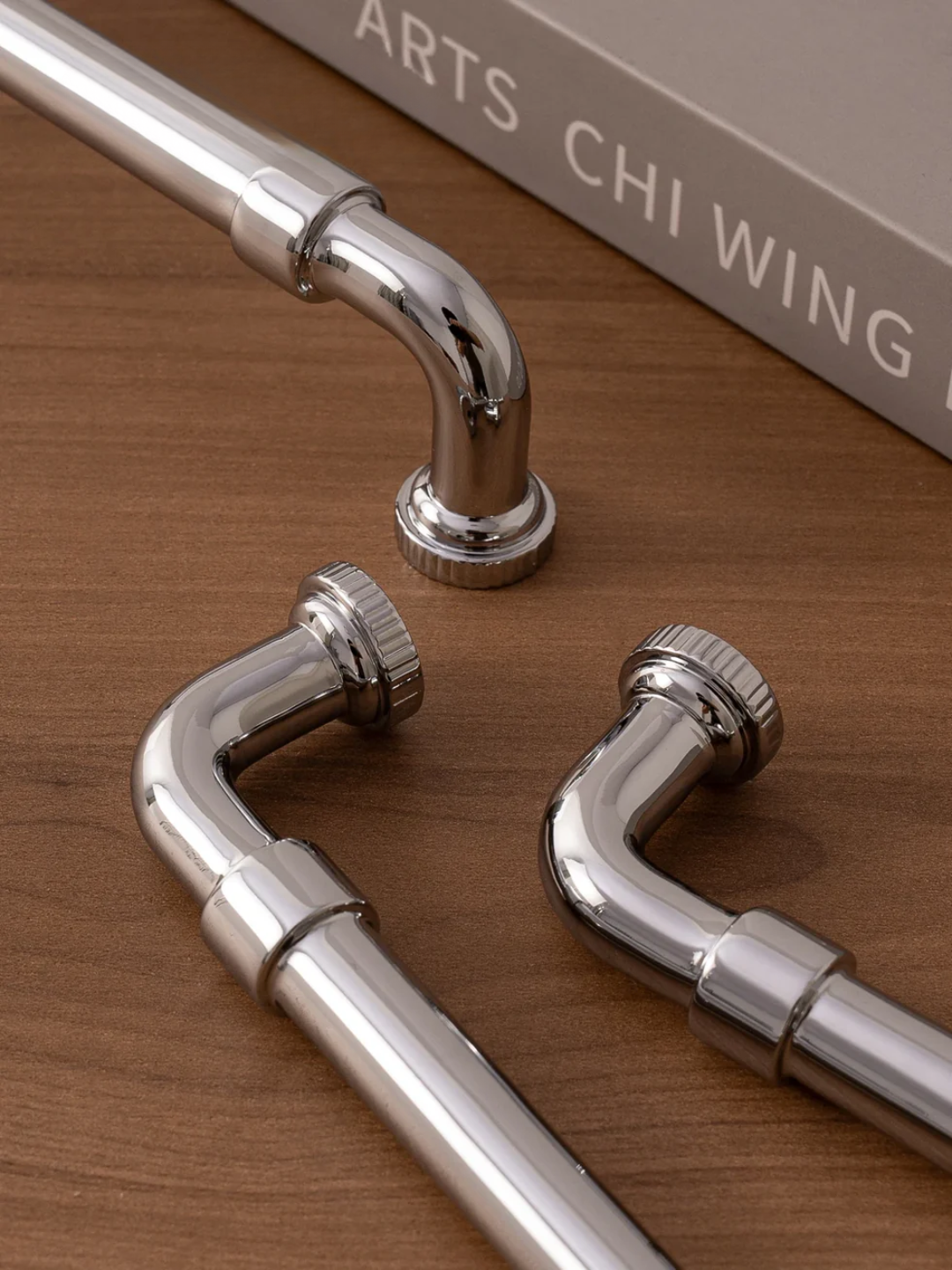 Metallic curtain rods on a wooden surface with a blurred background
