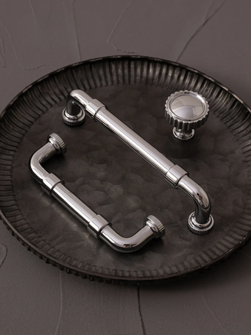 Metallic door handle and knobs on a textured black surface