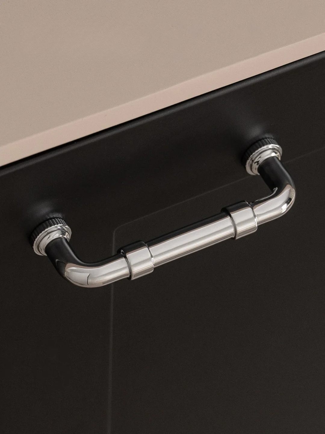 Metal handle on a black cabinet with a beige top