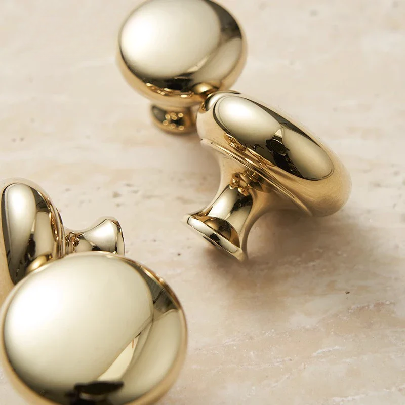 Gold earrings on a beige marble surface