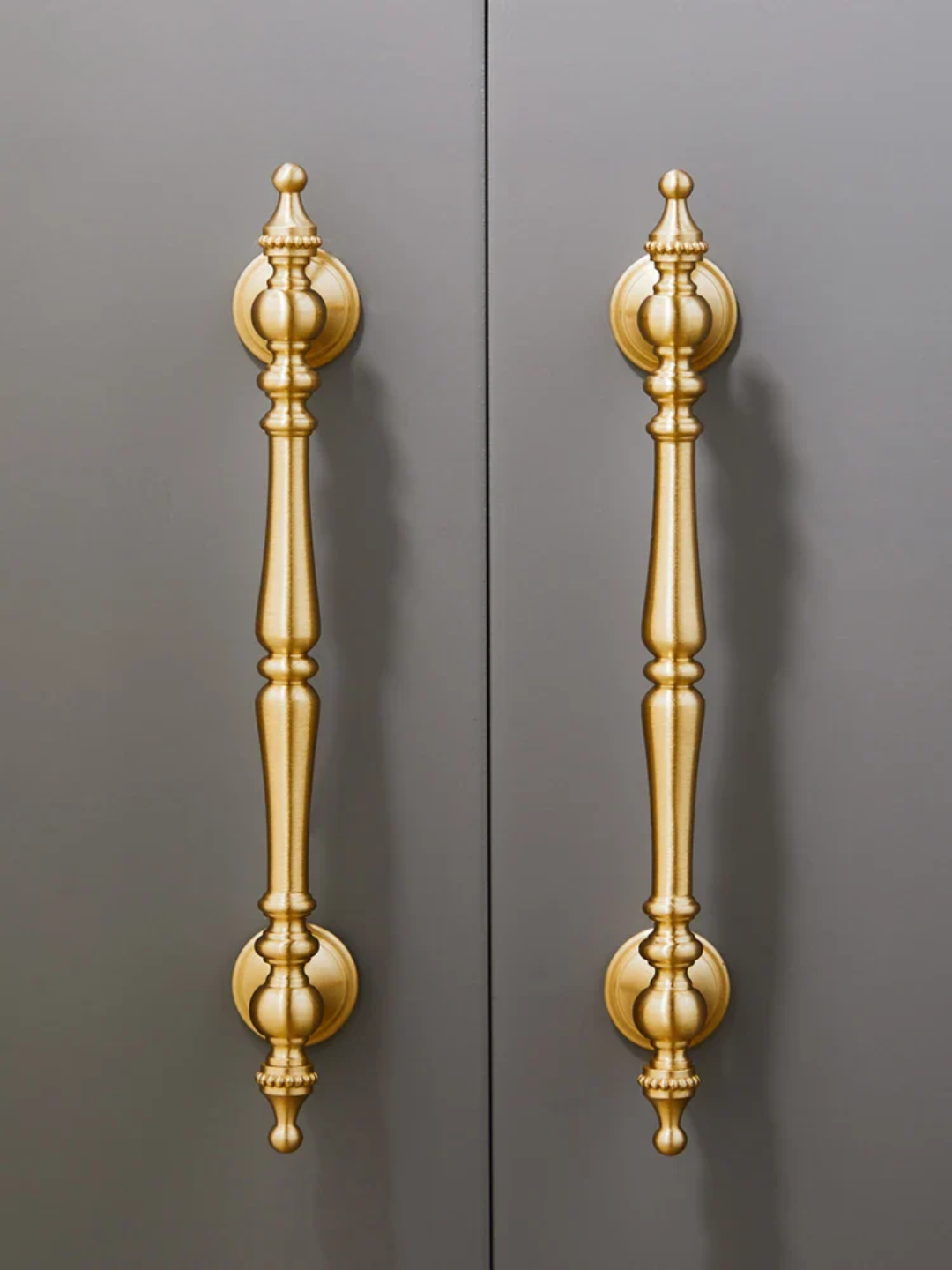 Pair of gold ornate door handles on a gray background