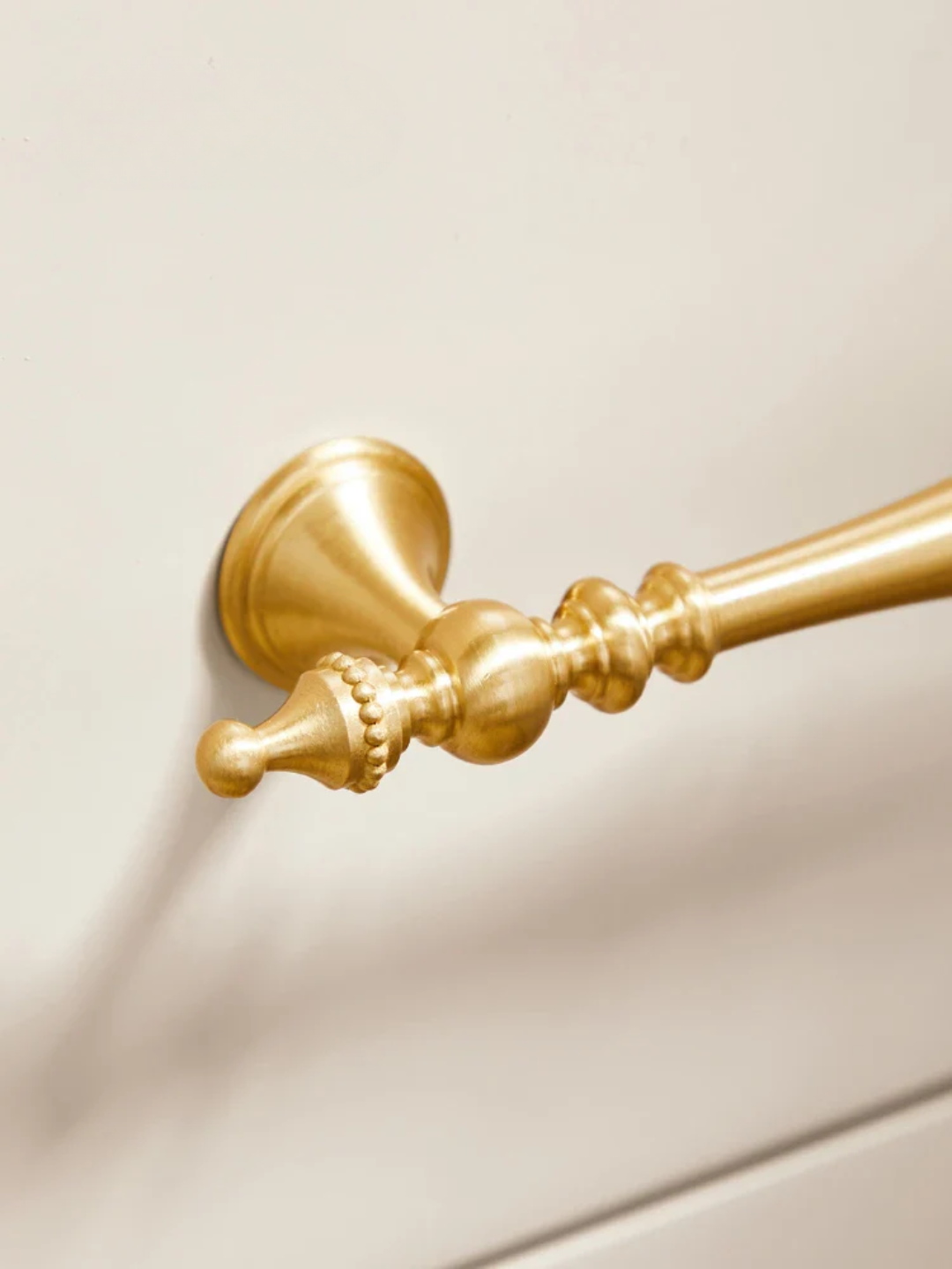 Gold towel bar on a beige wall