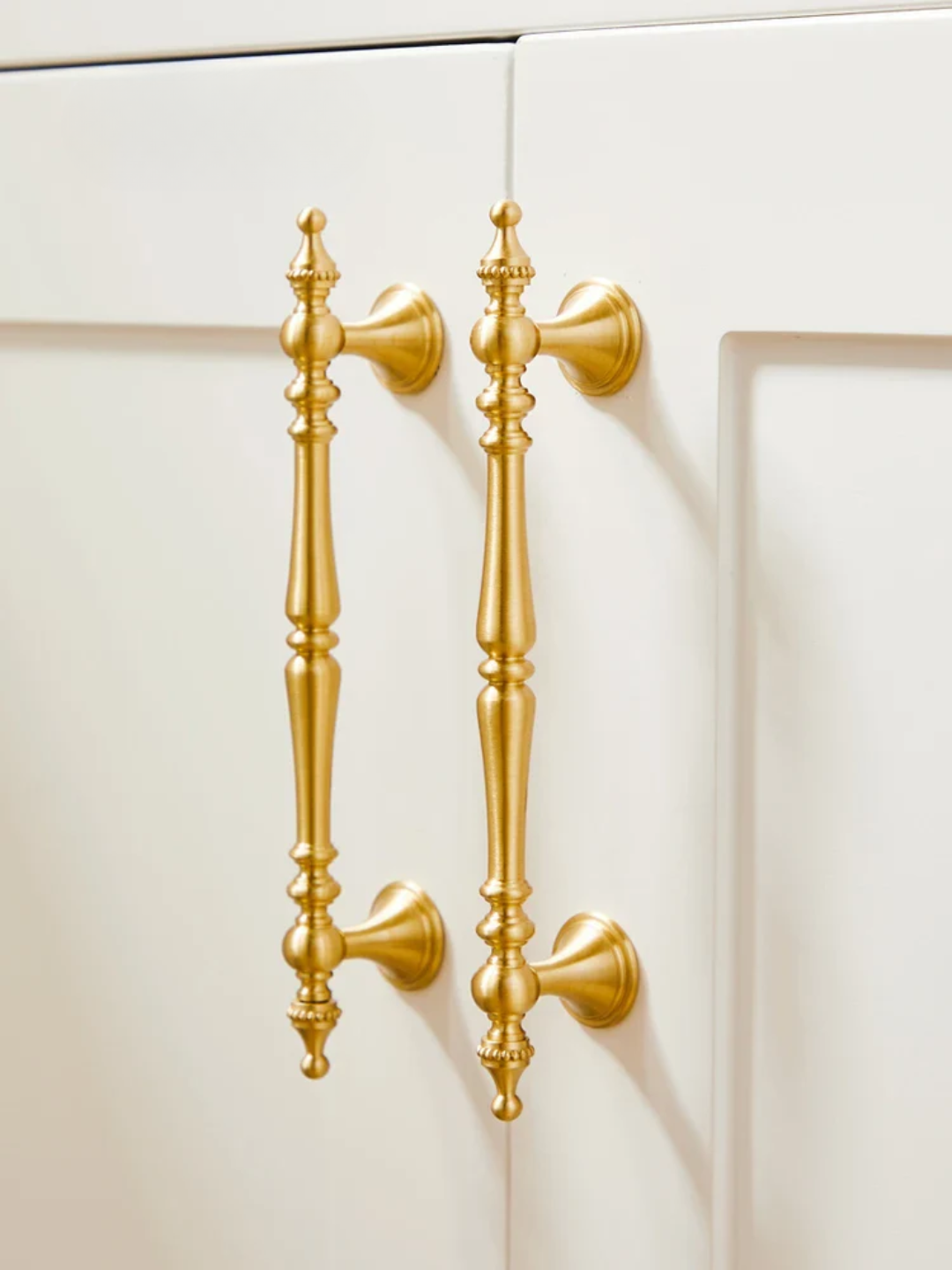Gold cabinet handles and knobs on a white background