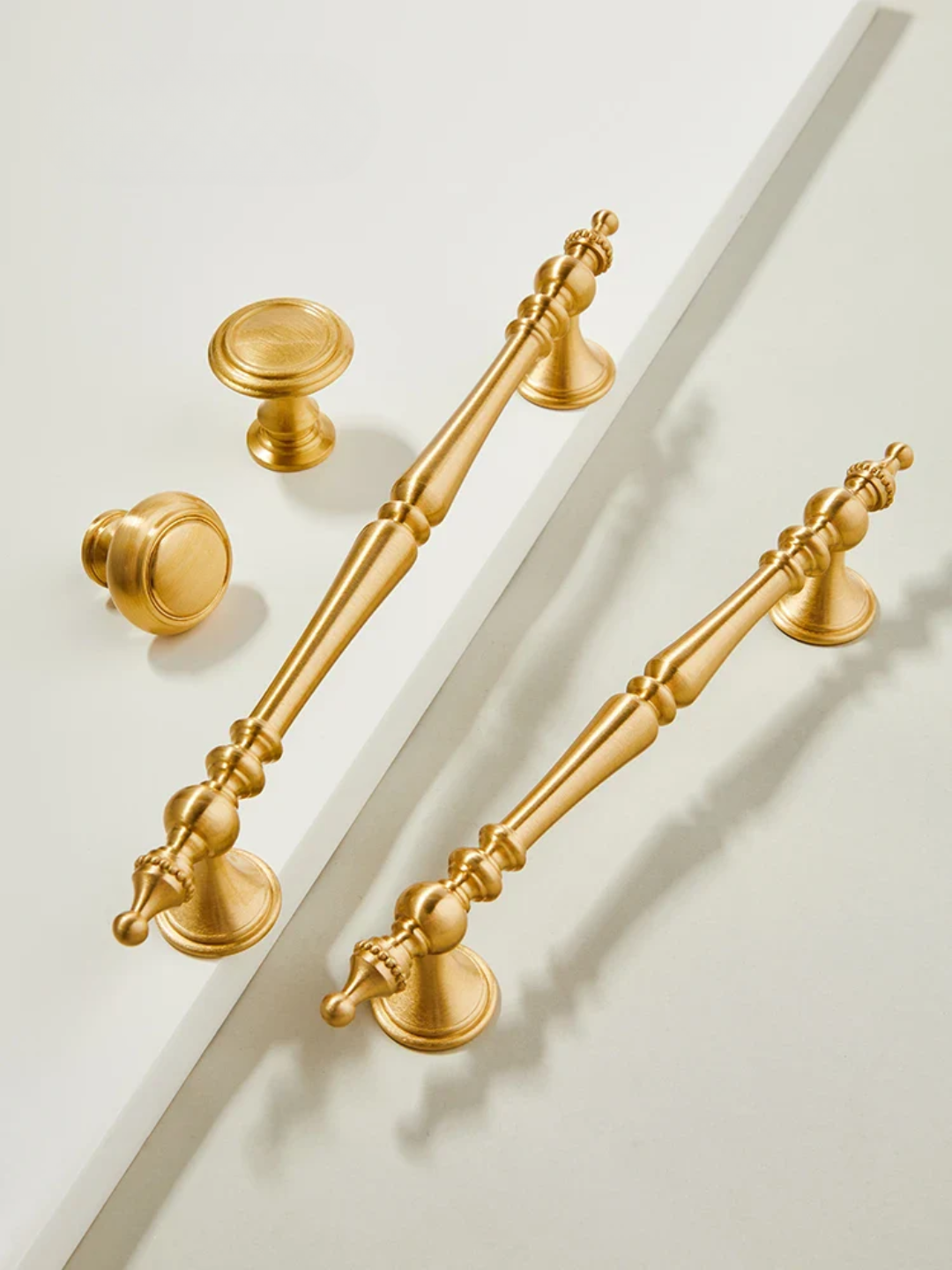 Gold cabinet handles and knobs on a white background