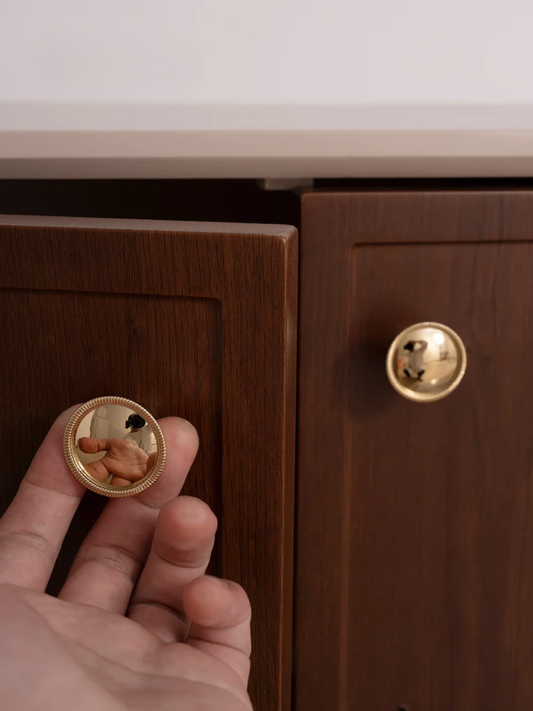 Hand holding a gold coin with a cabinet in the background