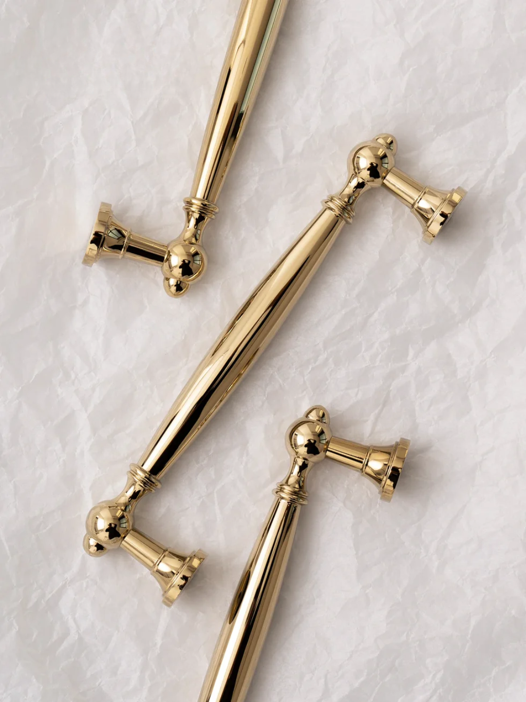 Three gold door handles on a textured white surface