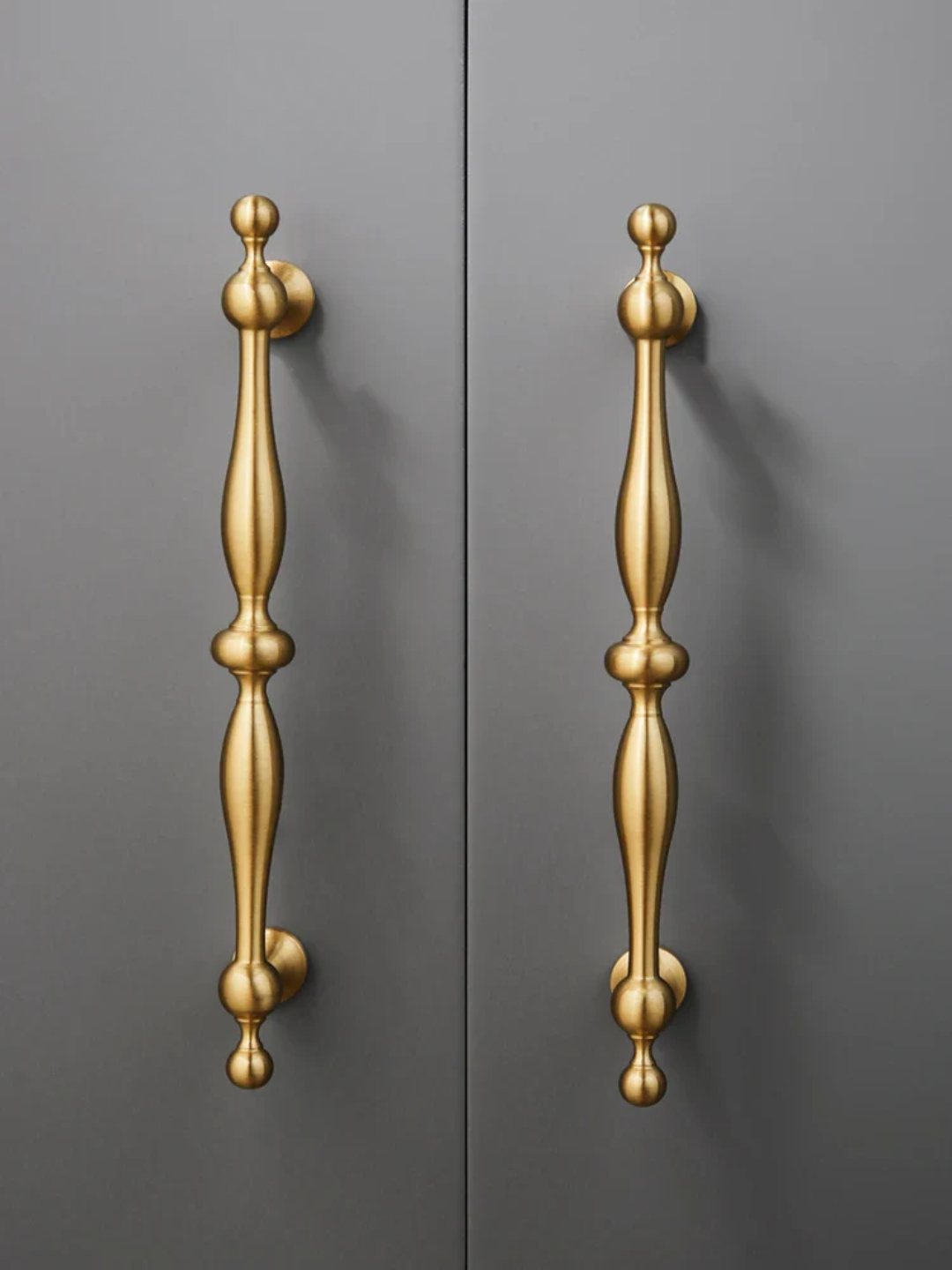 Pair of gold door handles on a gray background