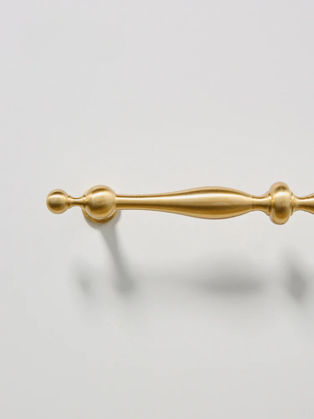 Gold cabinet handle on a light gray background