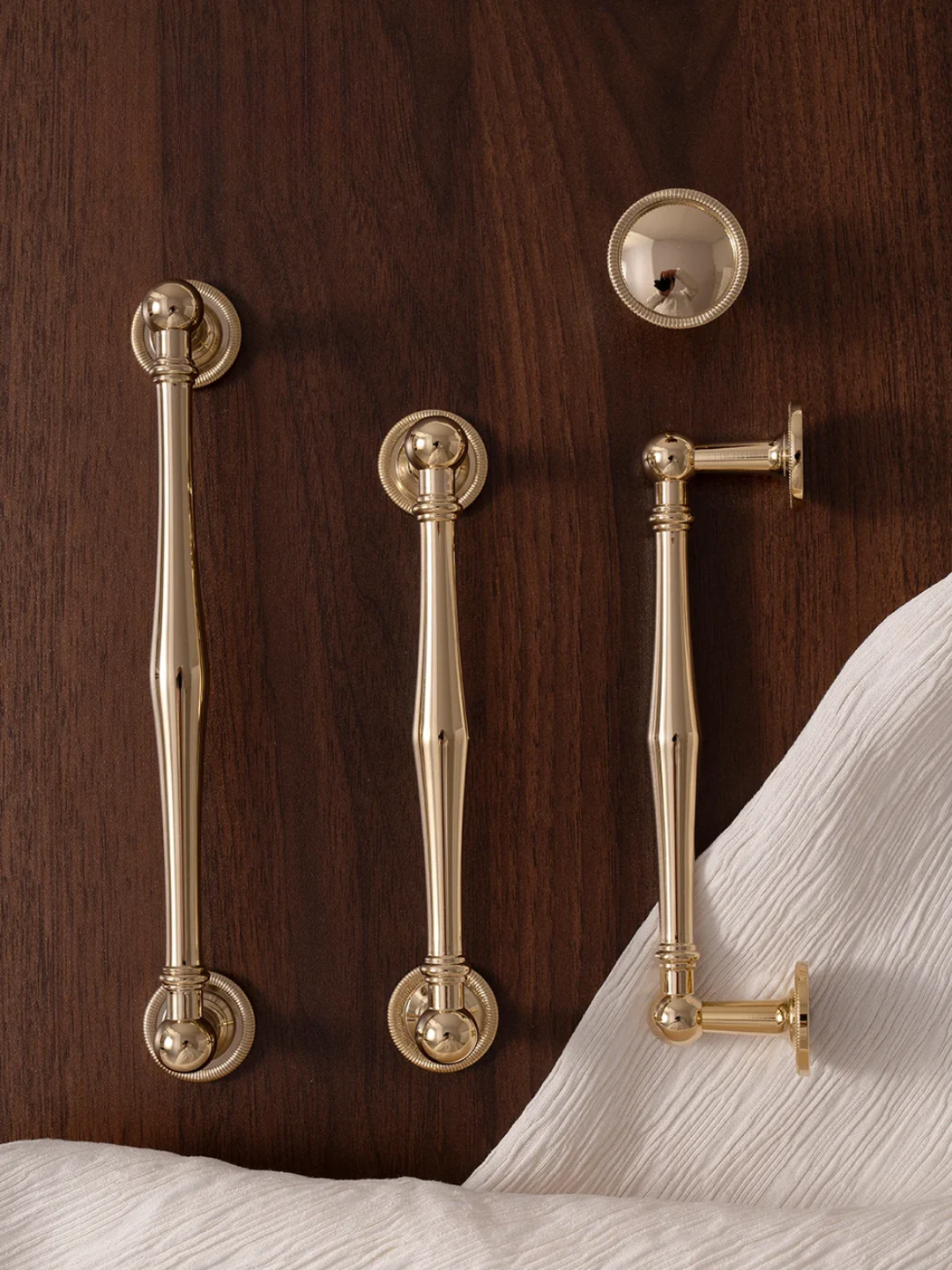 Brass handles on a wooden cabinet with white fabric