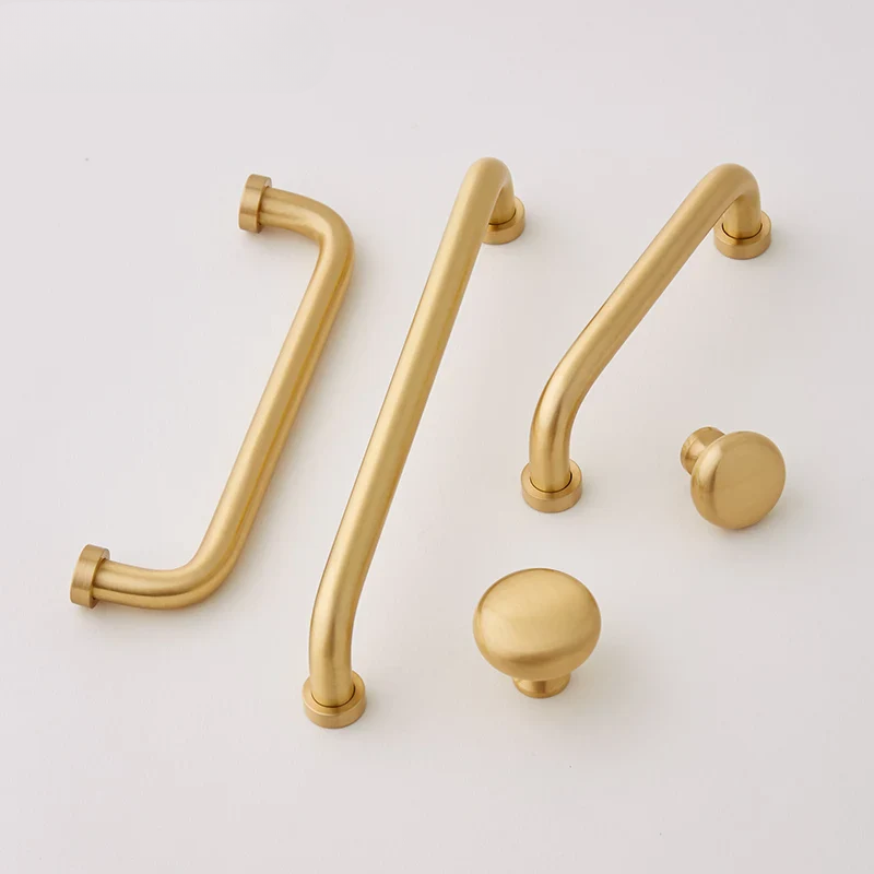 Set of gold cabinet handles and knobs on a light gray background