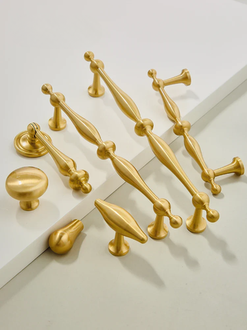 Collection of gold cabinet handles on a white background