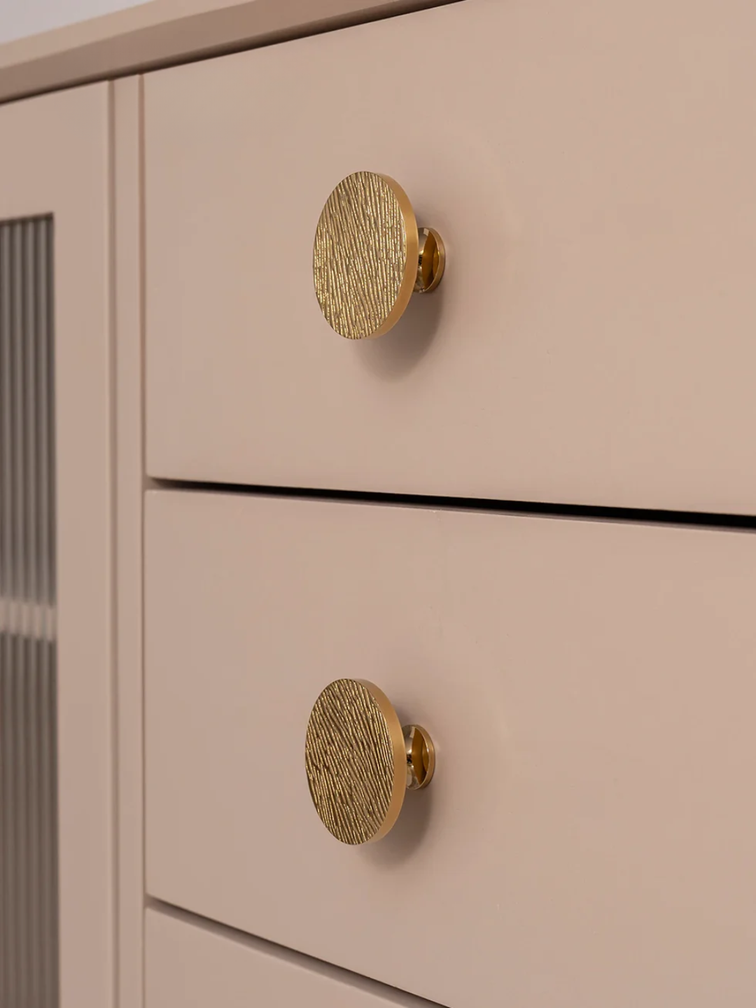 Close-up of a beige cabinet with gold round knobs