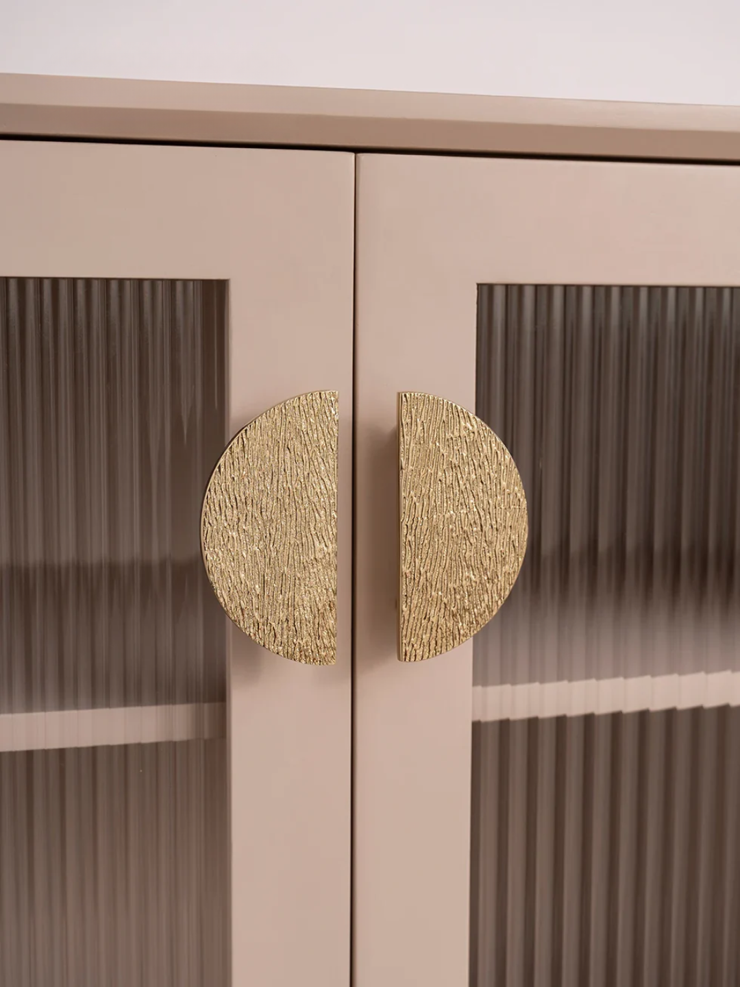 Close-up of a cabinet with gold circular handles on a beige background
