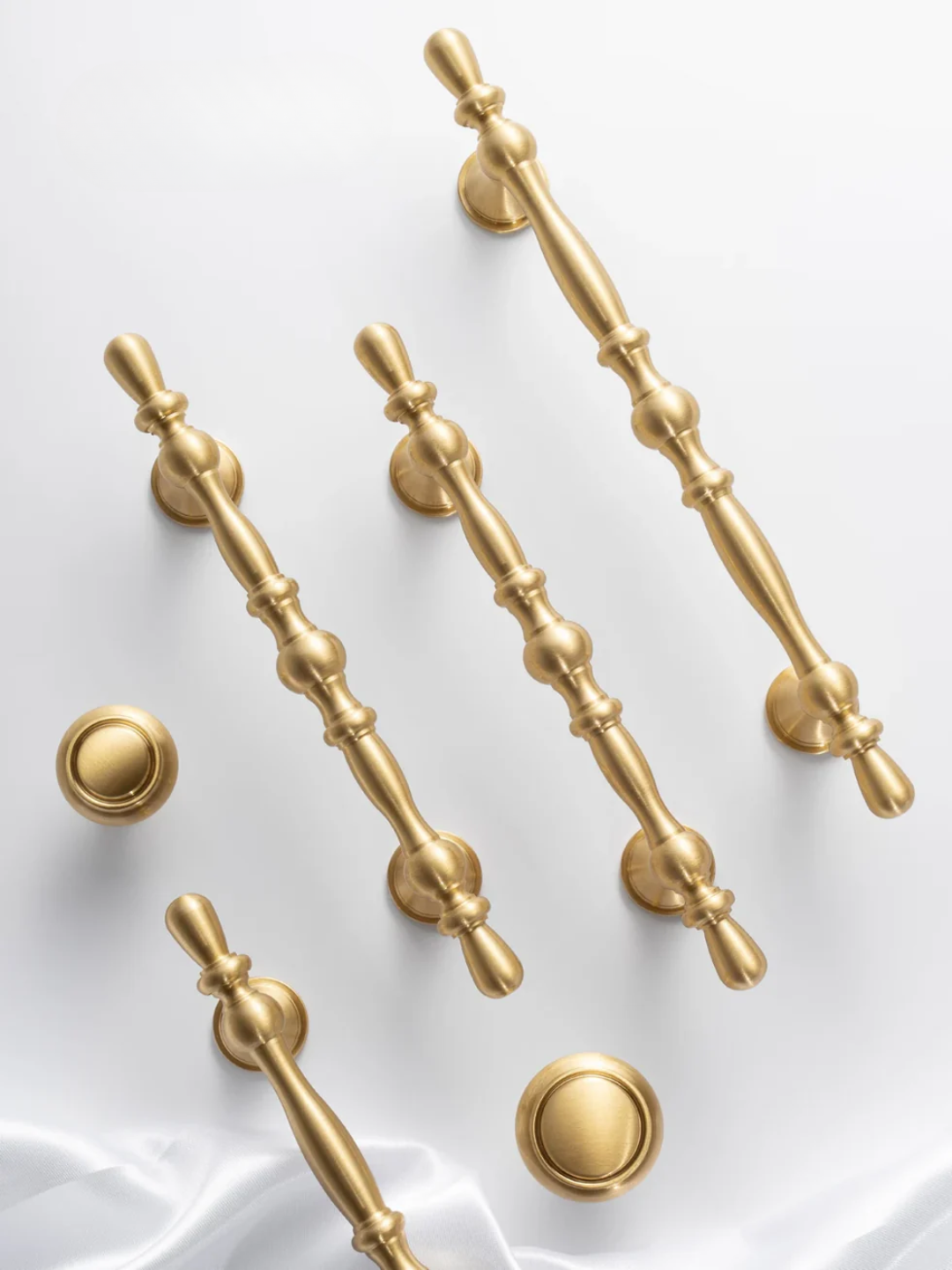 Set of gold cabinet handles and knobs on a white background