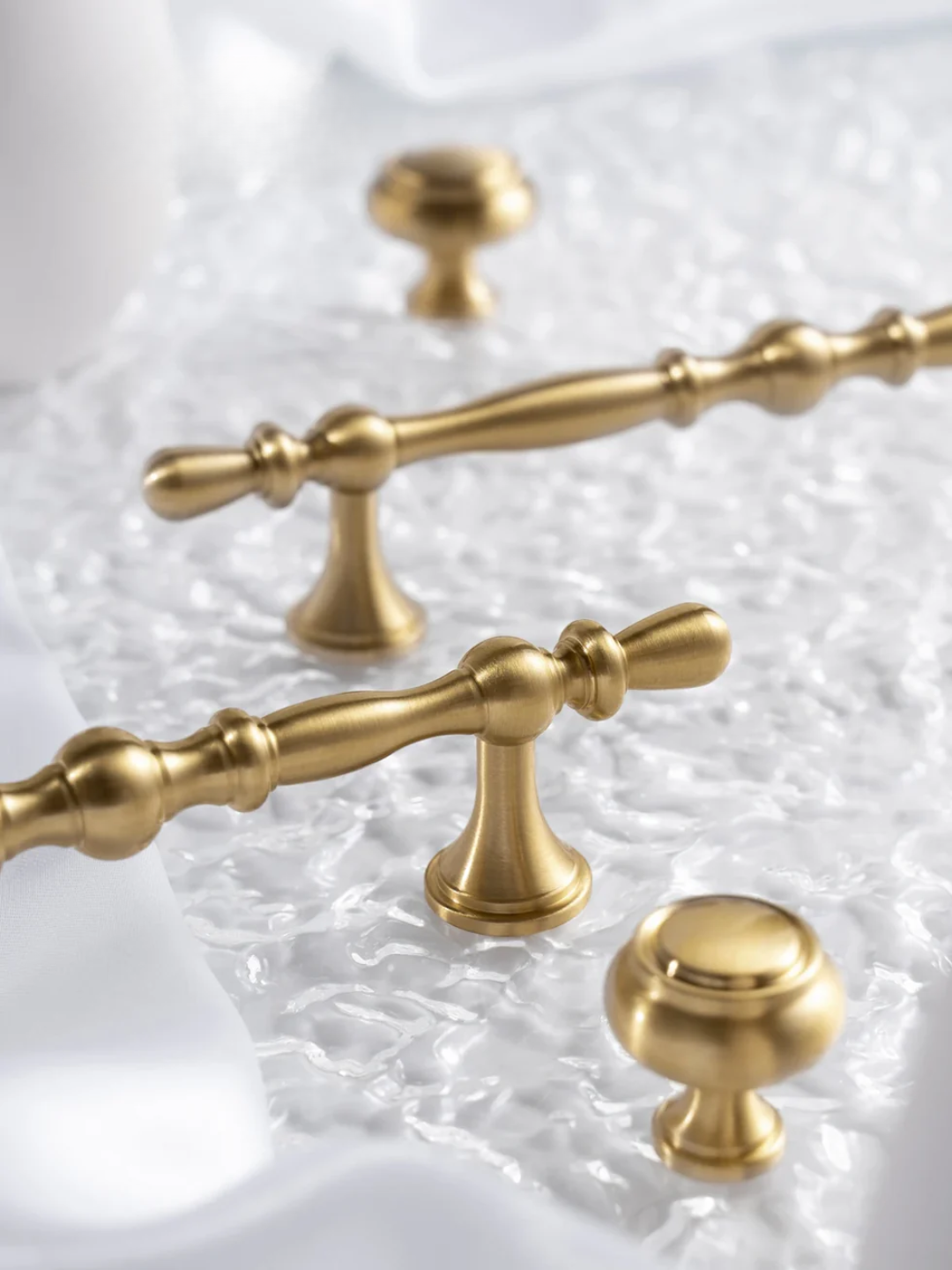 Gold cabinet handles on a textured white background