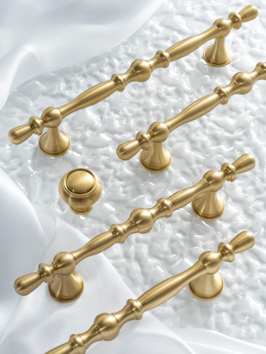 Gold cabinet handles and knobs on a textured white background