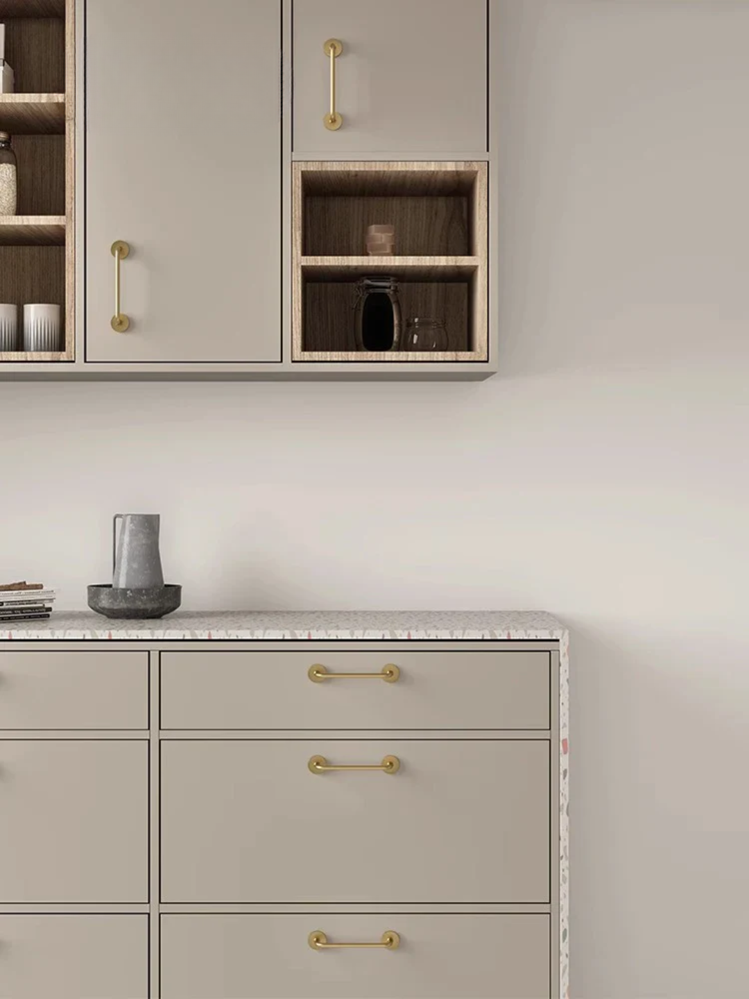 Gray kitchen cabinets with gold handles on a light gray wall.