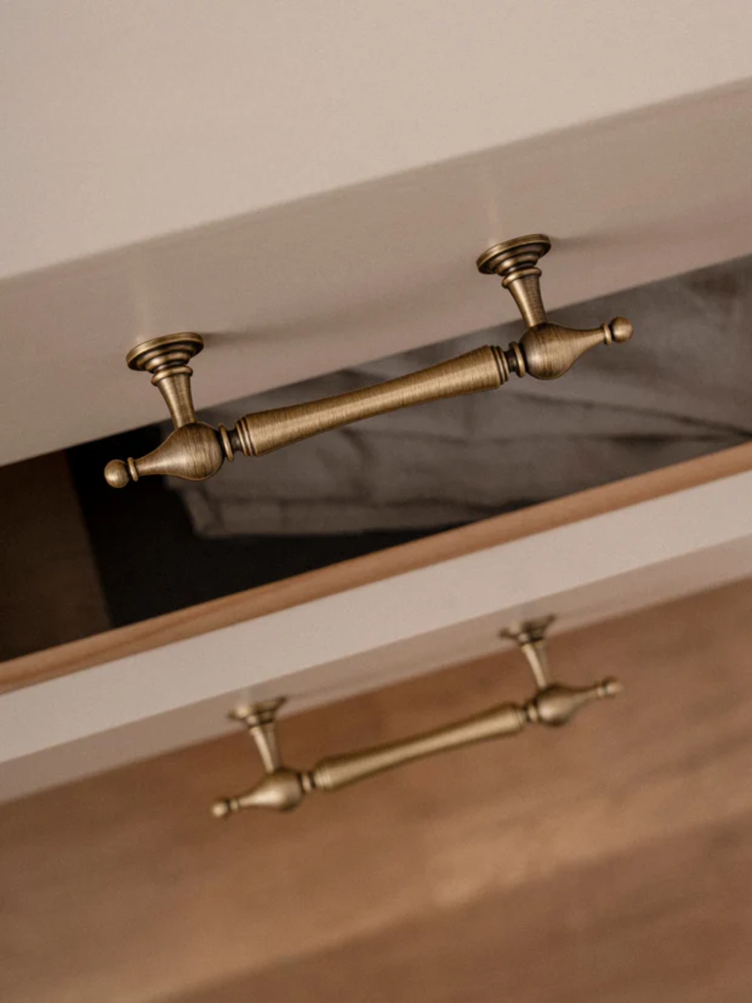 Close-up of a wooden drawer with brass handles on a neutral background