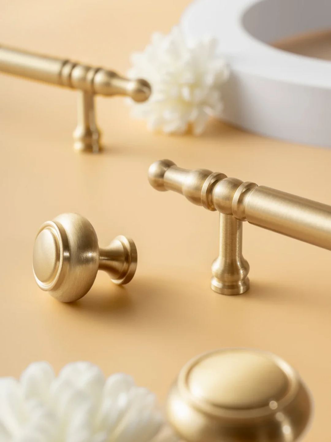 Gold bathroom fixtures including handles and knobs on a beige surface.