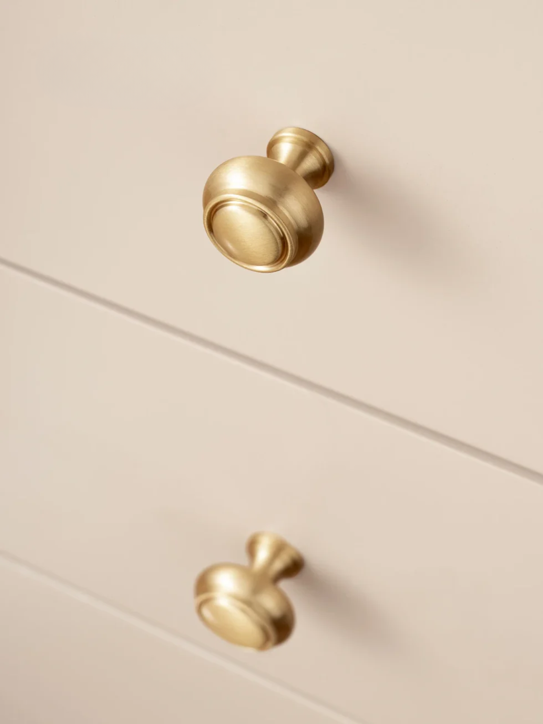 Close-up of gold cabinet knobs on a beige surface