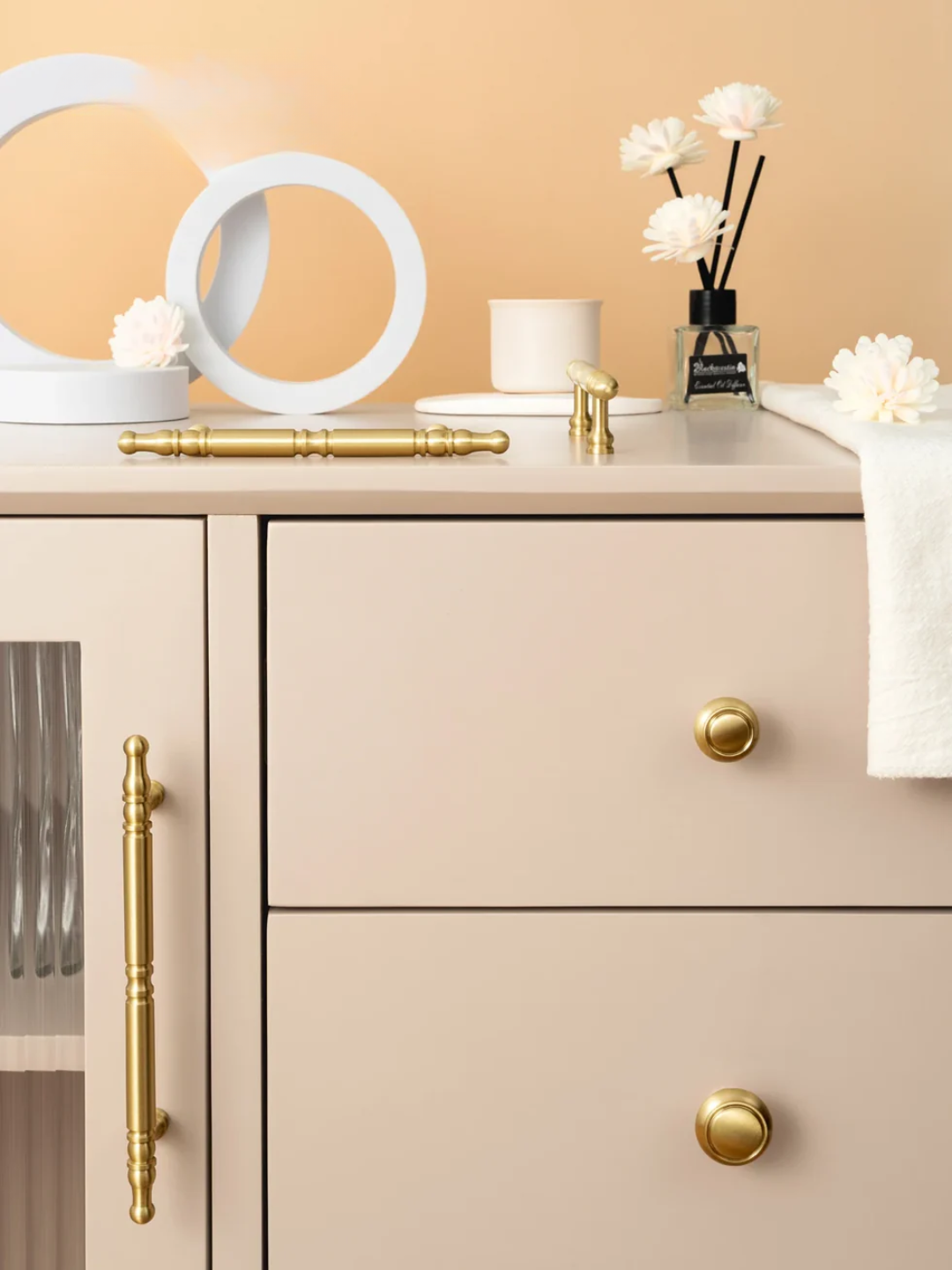 Beige cabinet with gold handles and decorative items on a beige background