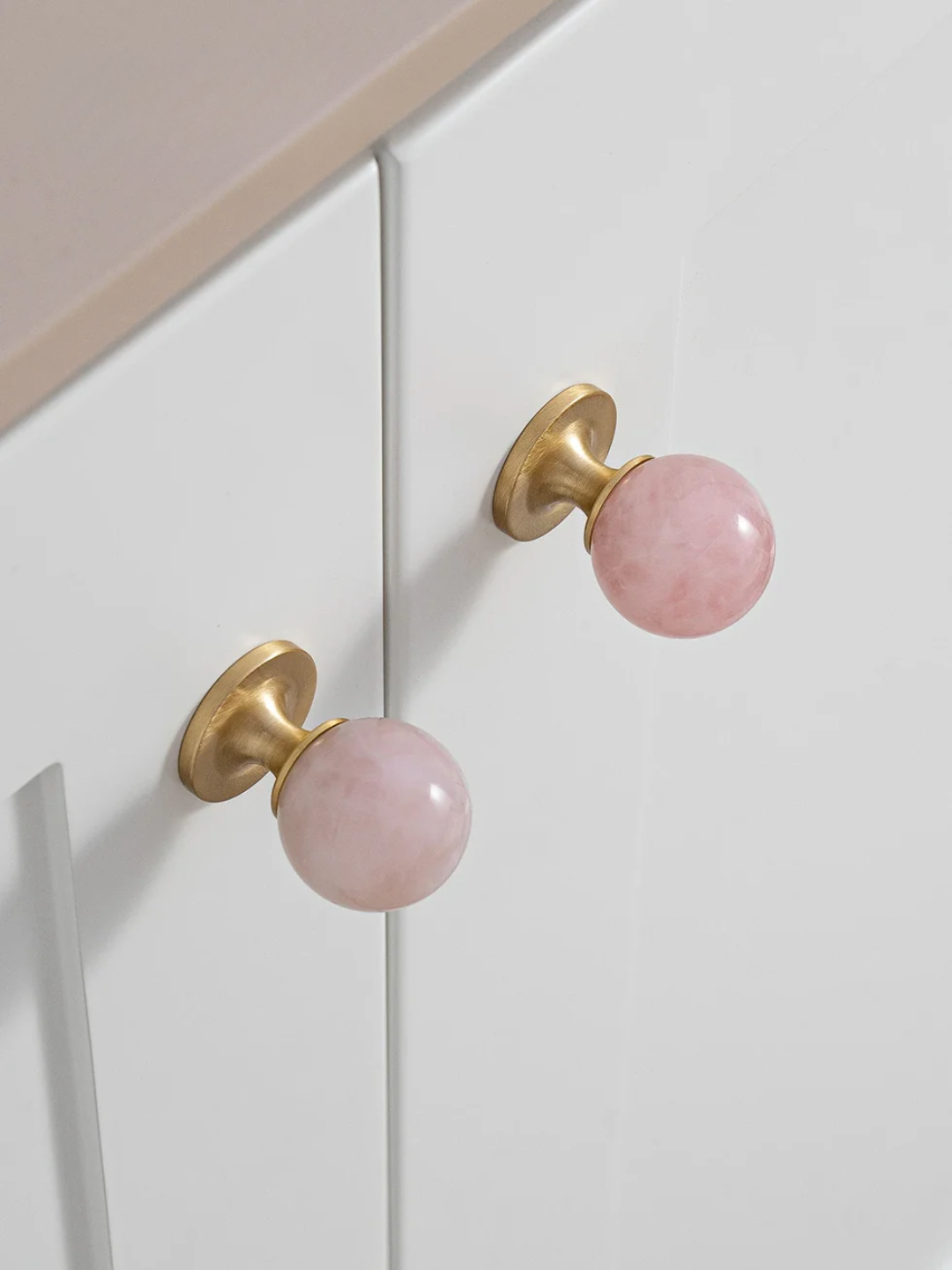 Cabinet doors with pink knobs on a white cabinet