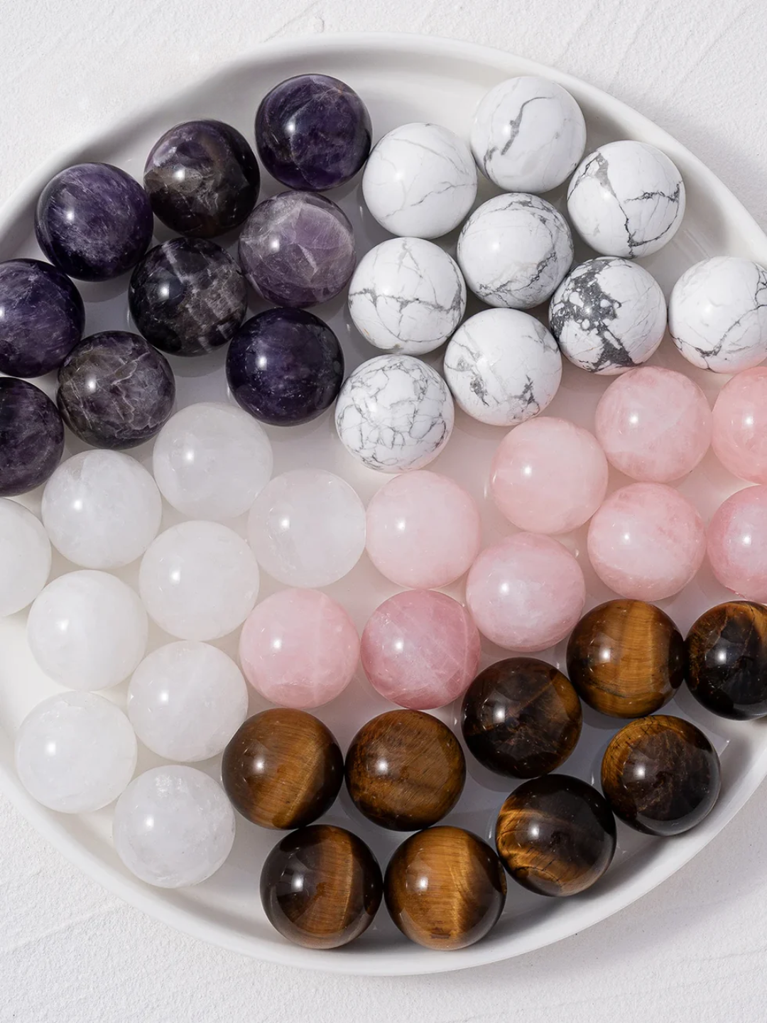 Assorted gemstone beads on a white plate
