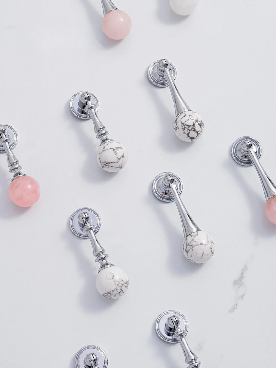Silver earrings with pink and white gemstones on a light background