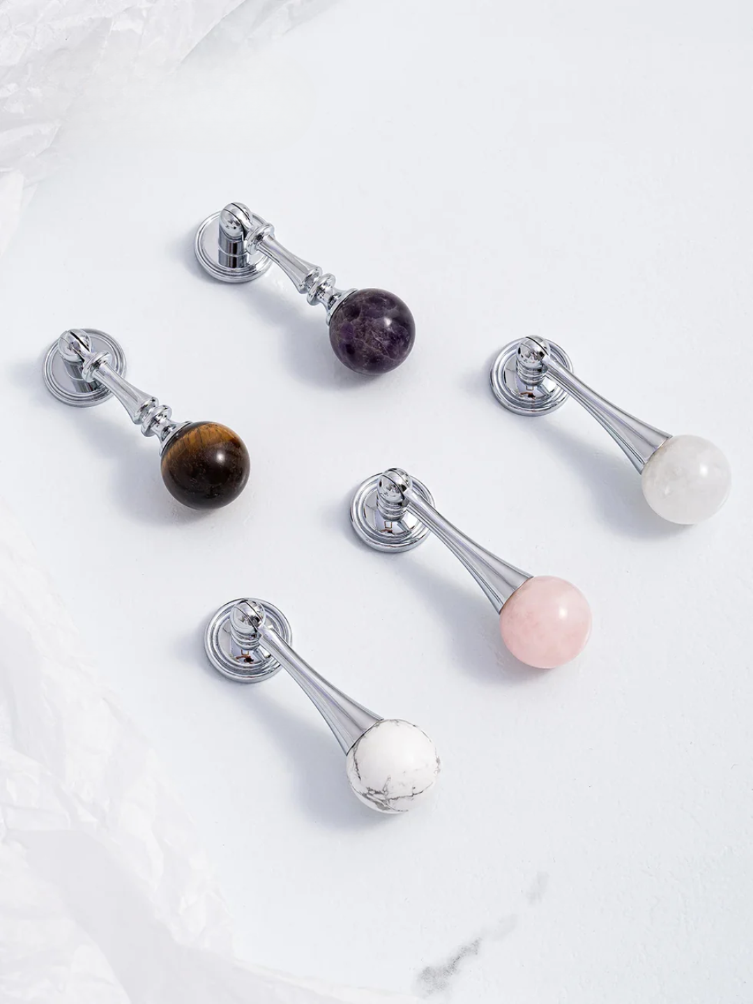 Set of decorative door handles with gemstone accents on a marble surface