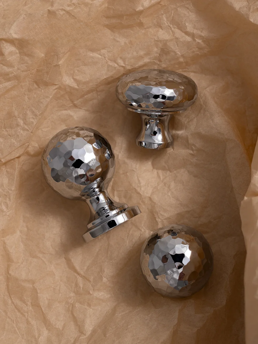 Three metallic door knobs on a crumpled brown paper background