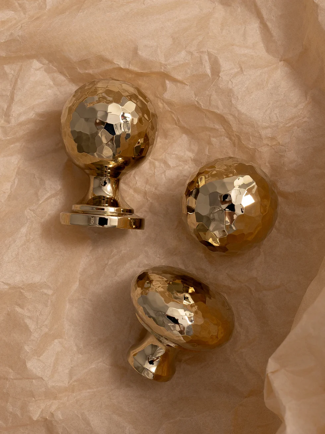 Three gold door handles on a textured beige surface