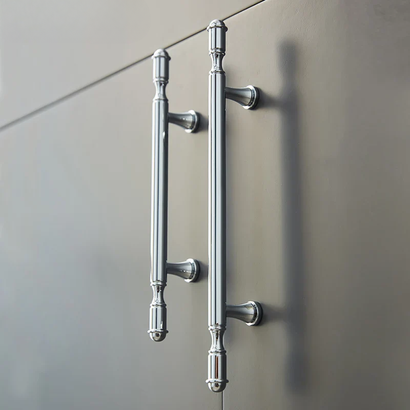Pair of silver door handles on a reflective surface