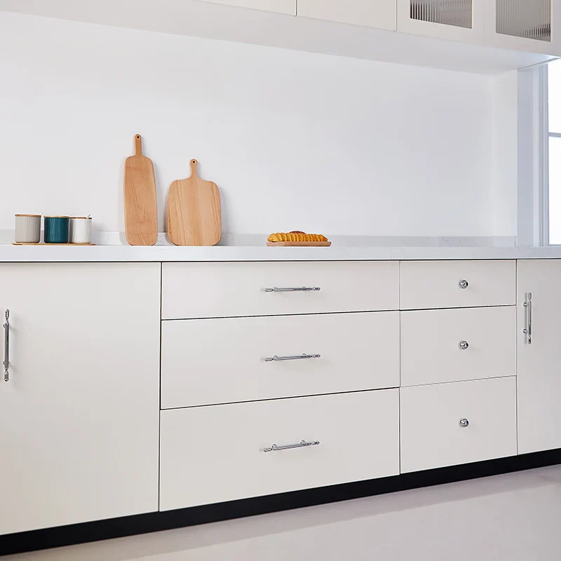 Set of chrome cabinet handles and knobs on a light gray background