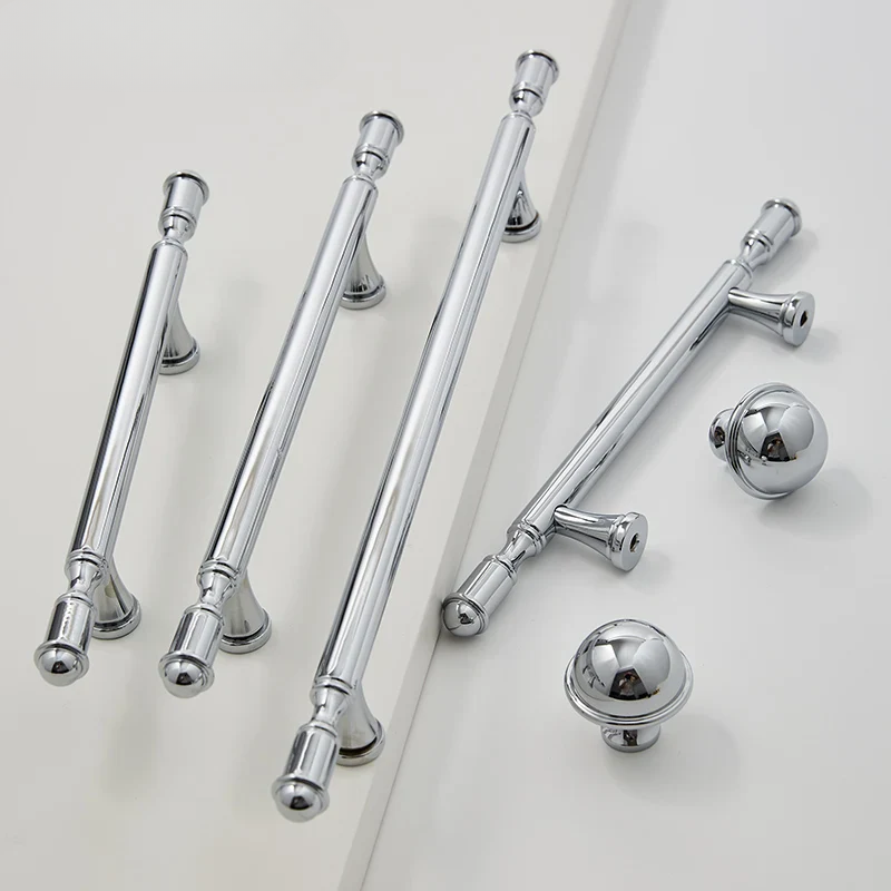 Set of chrome cabinet handles and knobs on a light gray background