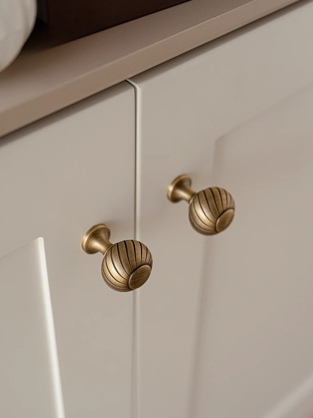 Close-up of a cabinet with brass knobs on a neutral background