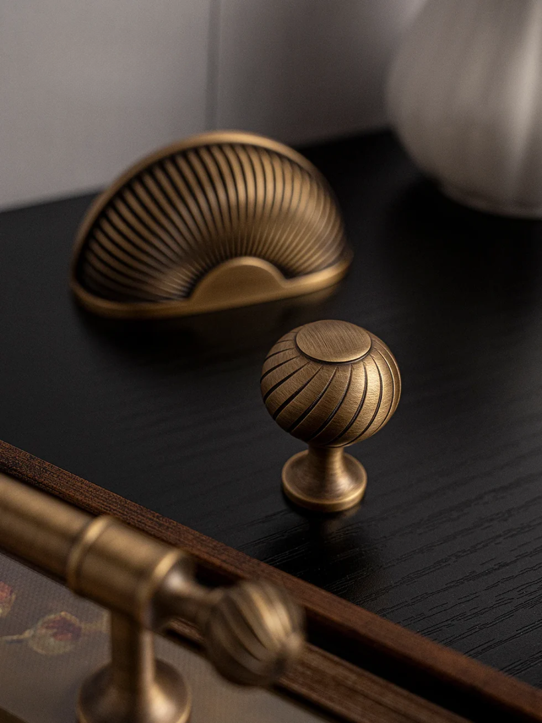 Bronze cabinet knobs on a dark surface with a neutral background