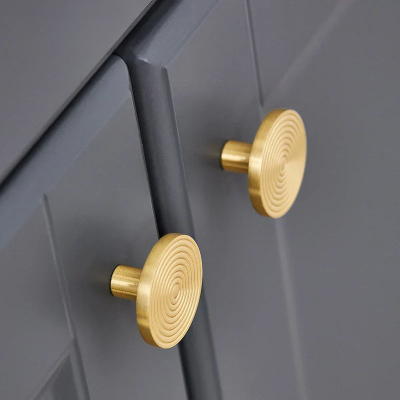 Gold cabinet knobs on a gray drawer