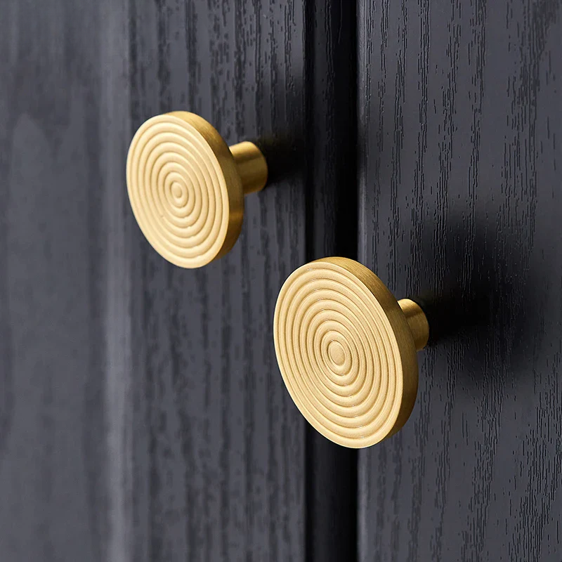 Gold circular door handles on a dark wooden door