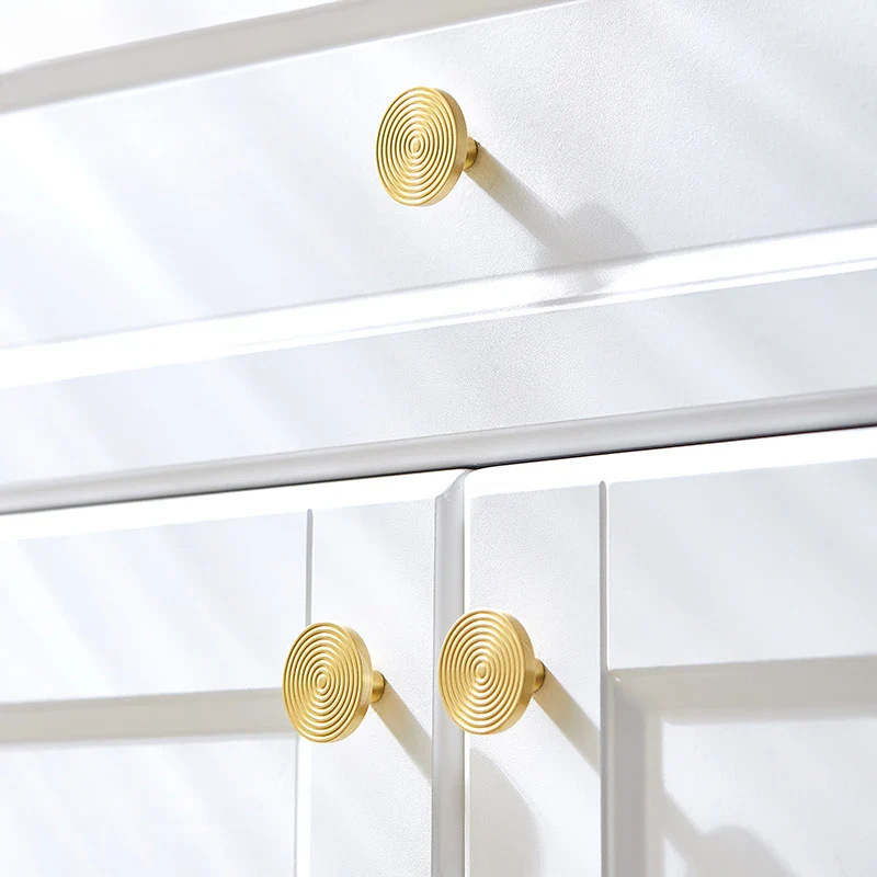 Gold spiral cabinet knobs on a white wooden cabinet