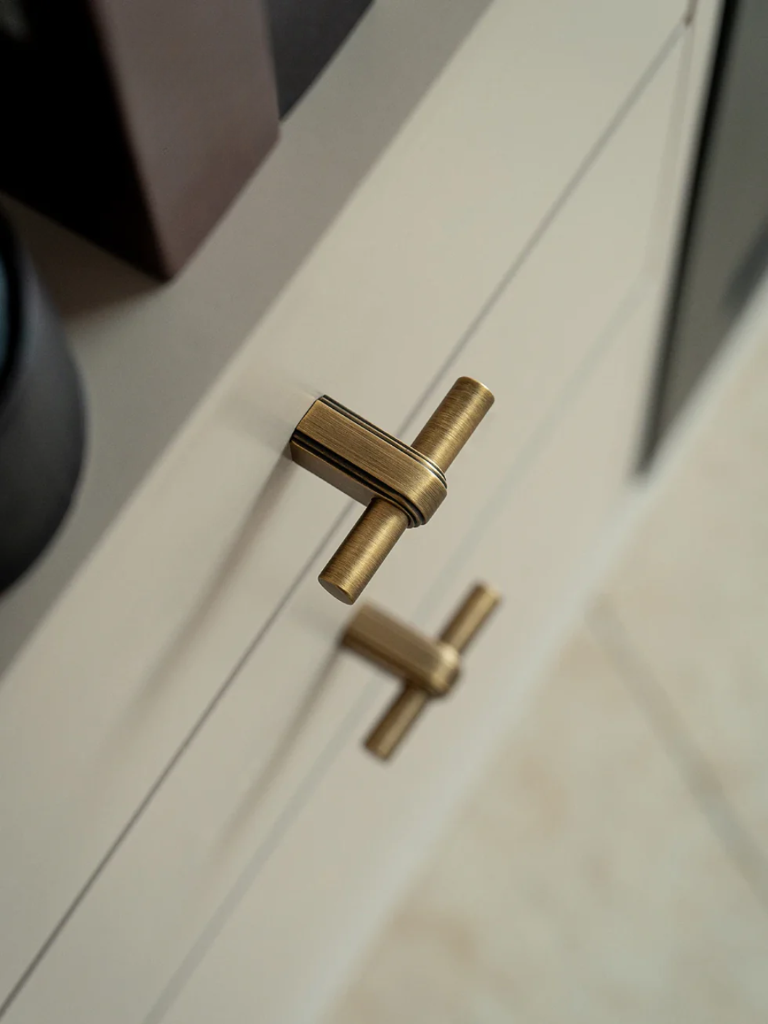 Close-up of a gold cabinet handle on a white cabinet door.