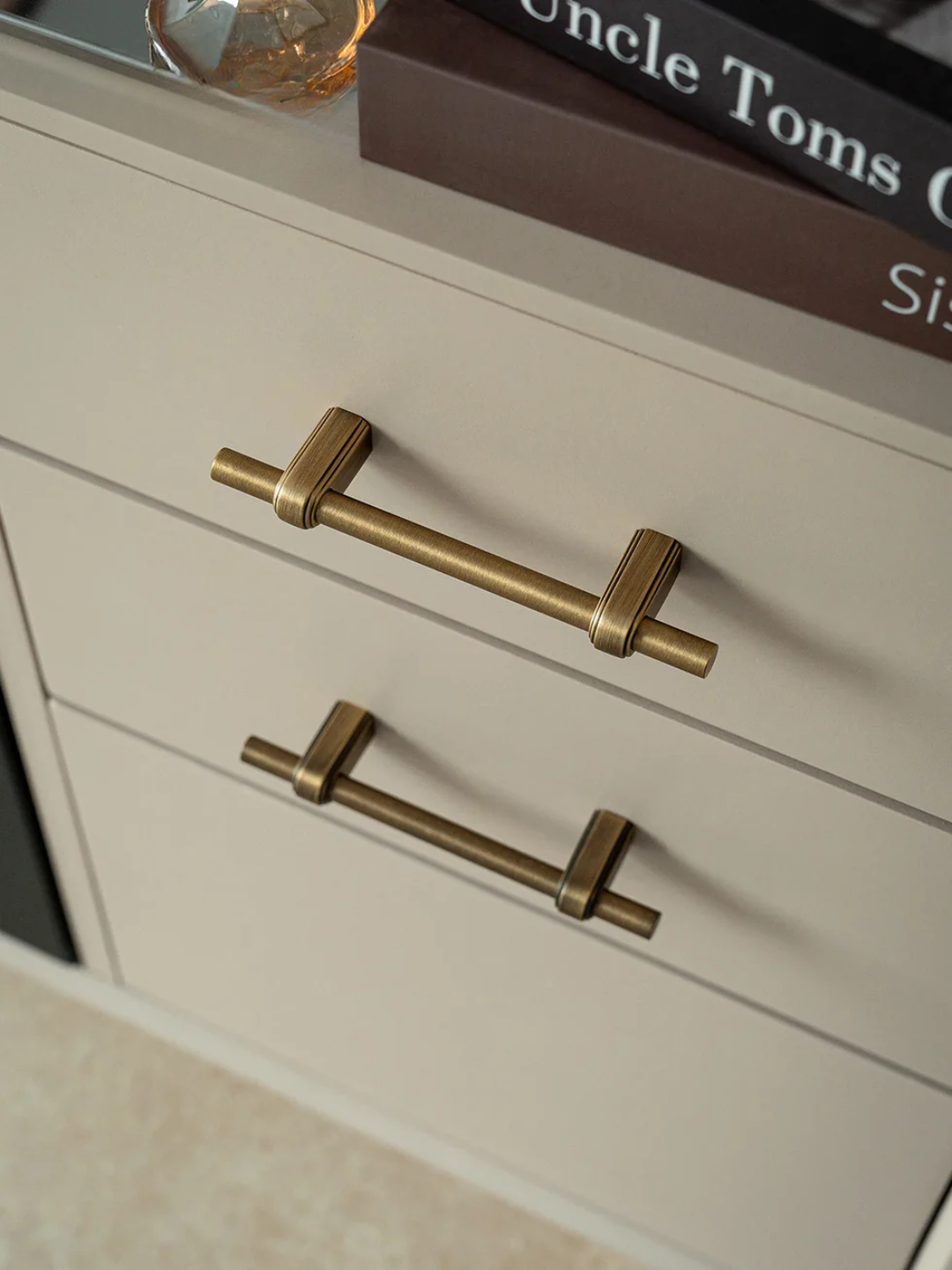 Brass cabinet handles on a light-colored wooden drawer