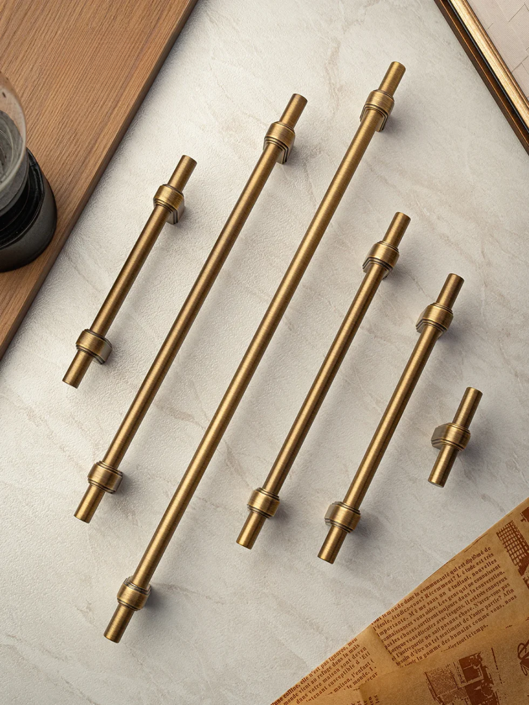 Set of gold cabinet handles on a light gray surface with a wooden edge.