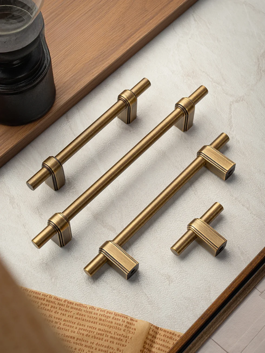 Set of gold cabinet handles on a light surface with a book underneath