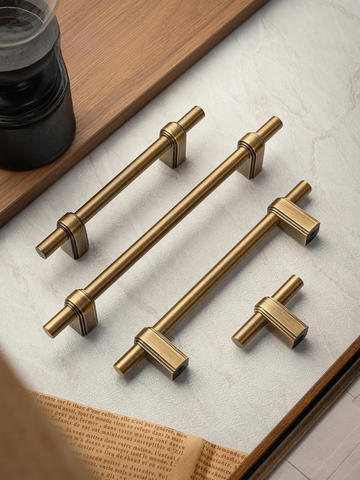 Set of gold cabinet handles on a light surface with a book underneath